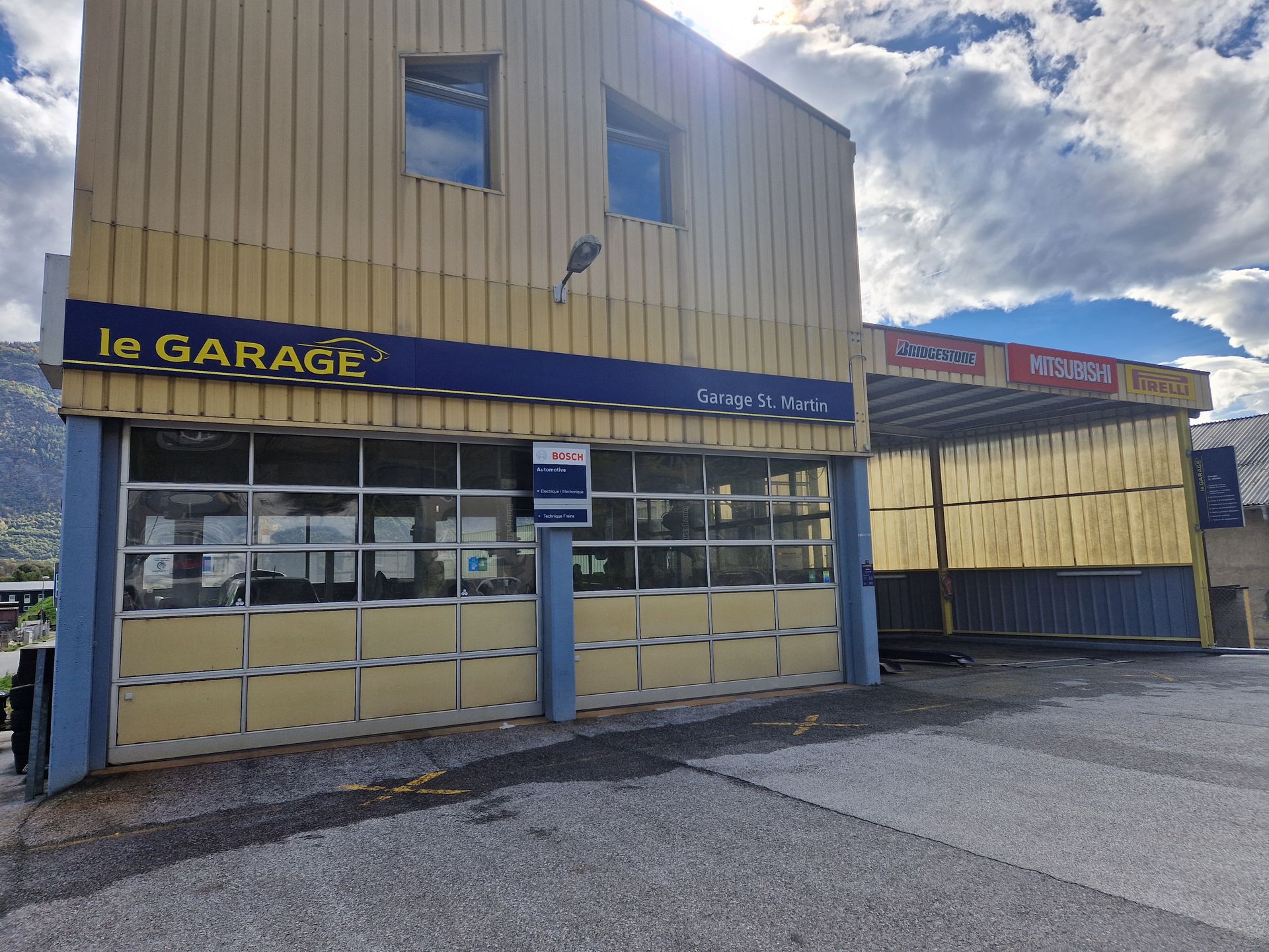 Un bâtiment jaune avec un panneau bleu indiquant dans le garage