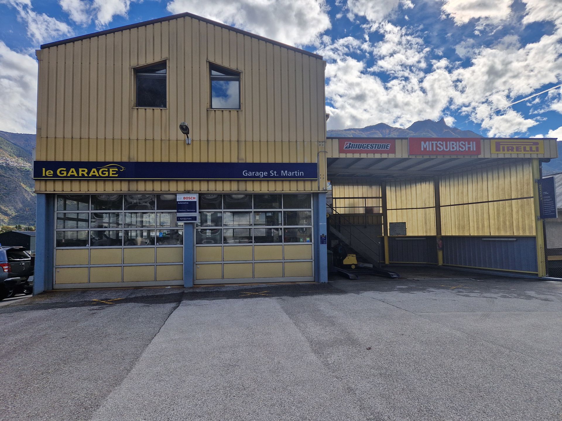 Un grand bâtiment avec beaucoup de fenêtres et une voiture garée devant.