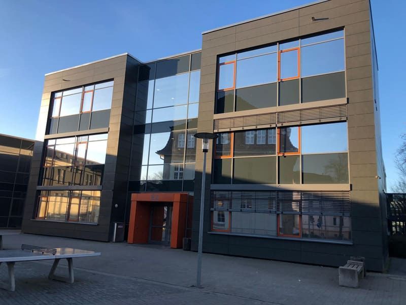 Ein großes Gebäude mit vielen Fenstern und einer Tischtennisplatte davor