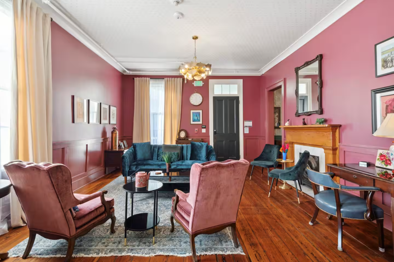 Bar with teal base, stools, chandelier, staircase, and checkered floor.