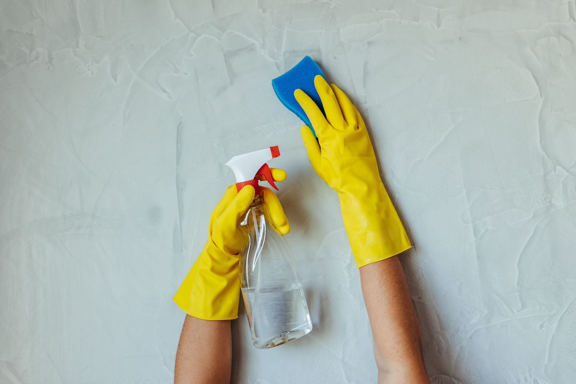 Gloved hands spraying cleaner on a countertop during Airbnb turnover cleaning