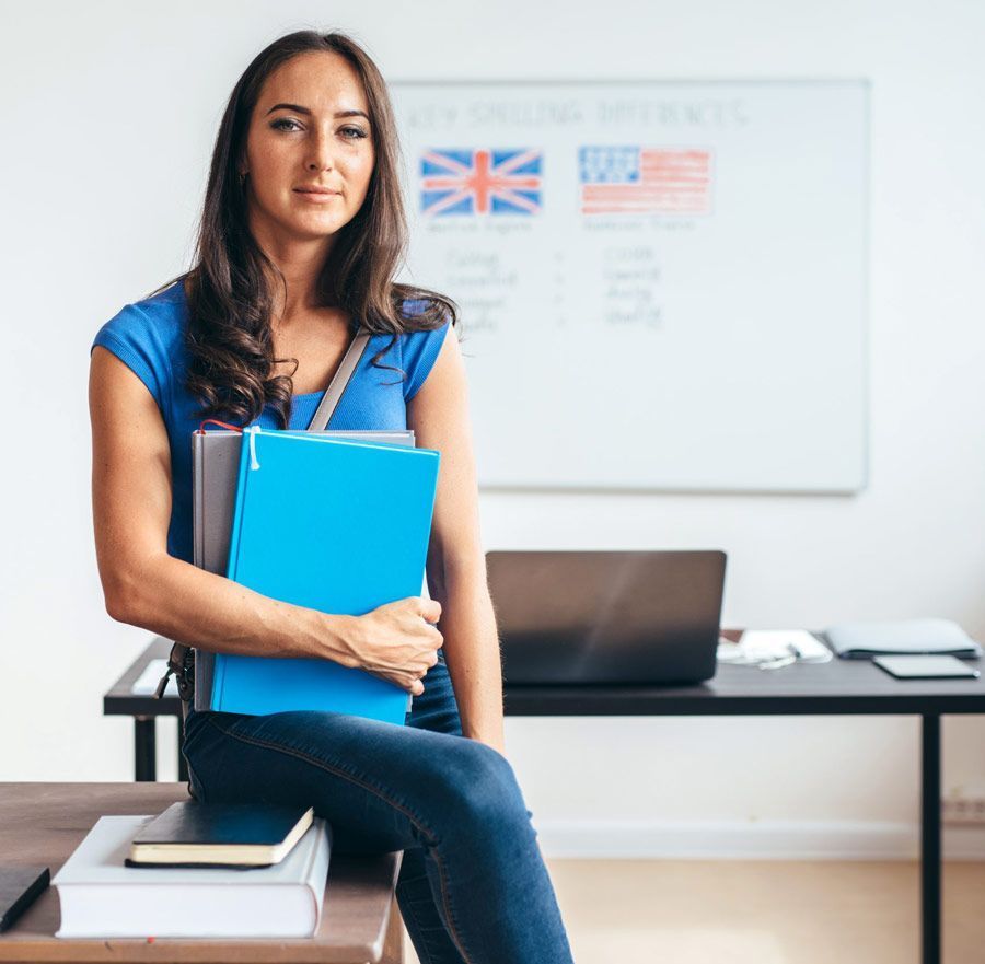 Una mujer está sentada en un escritorio sosteniendo una carpeta azul.
