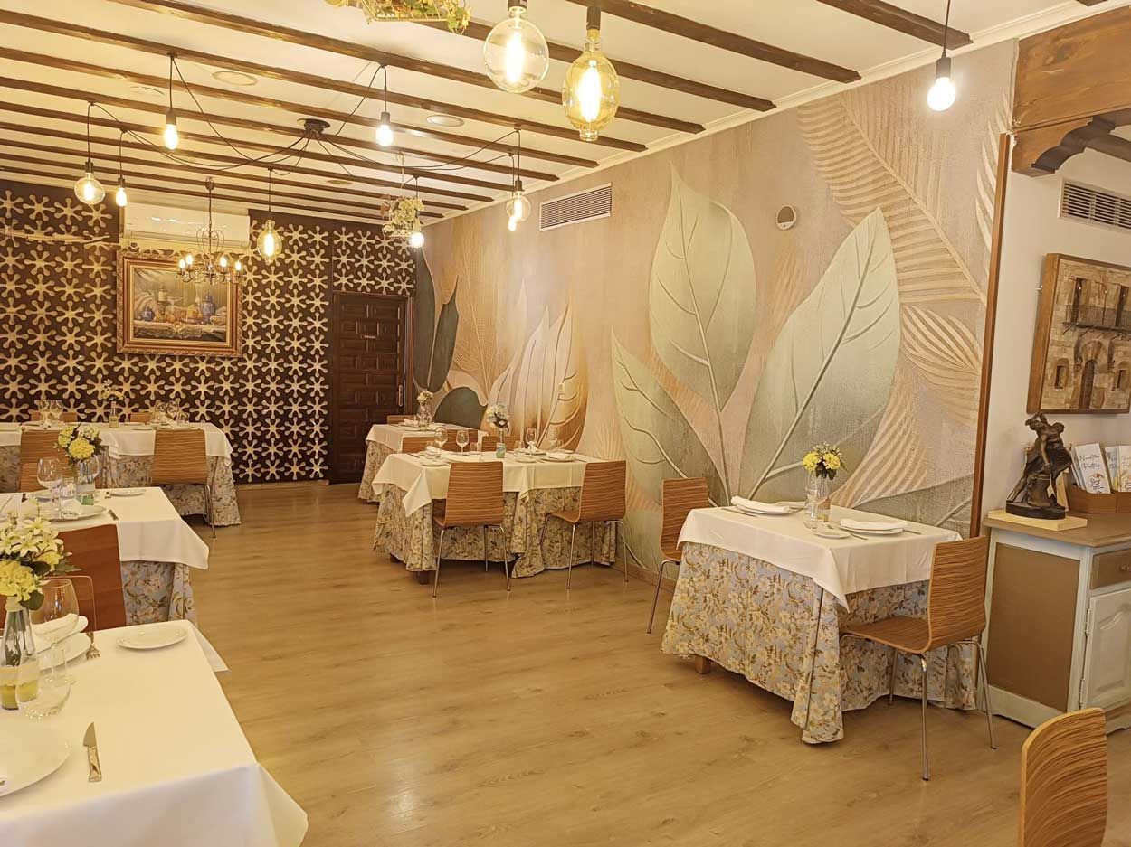 Un restaurante con mesas y sillas y una pared con hojas.