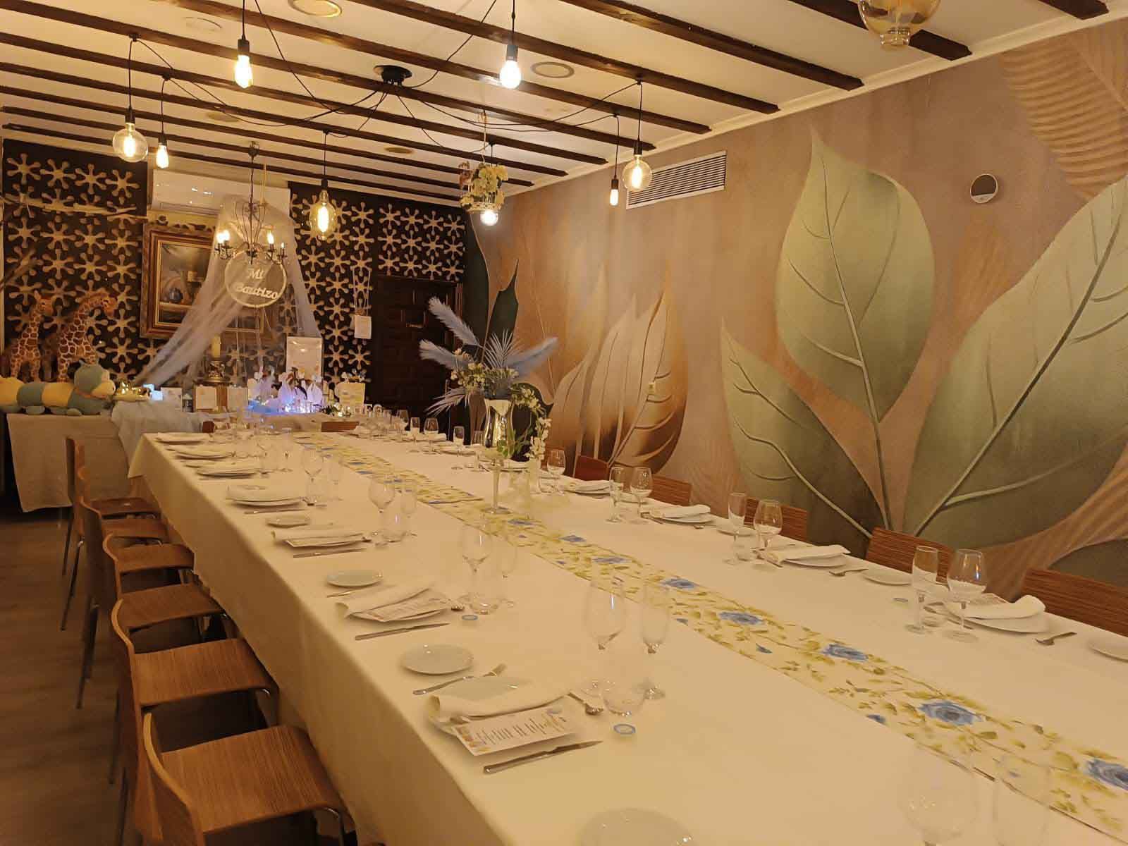 Hay una mesa larga con platos y vasos encima en una habitación.