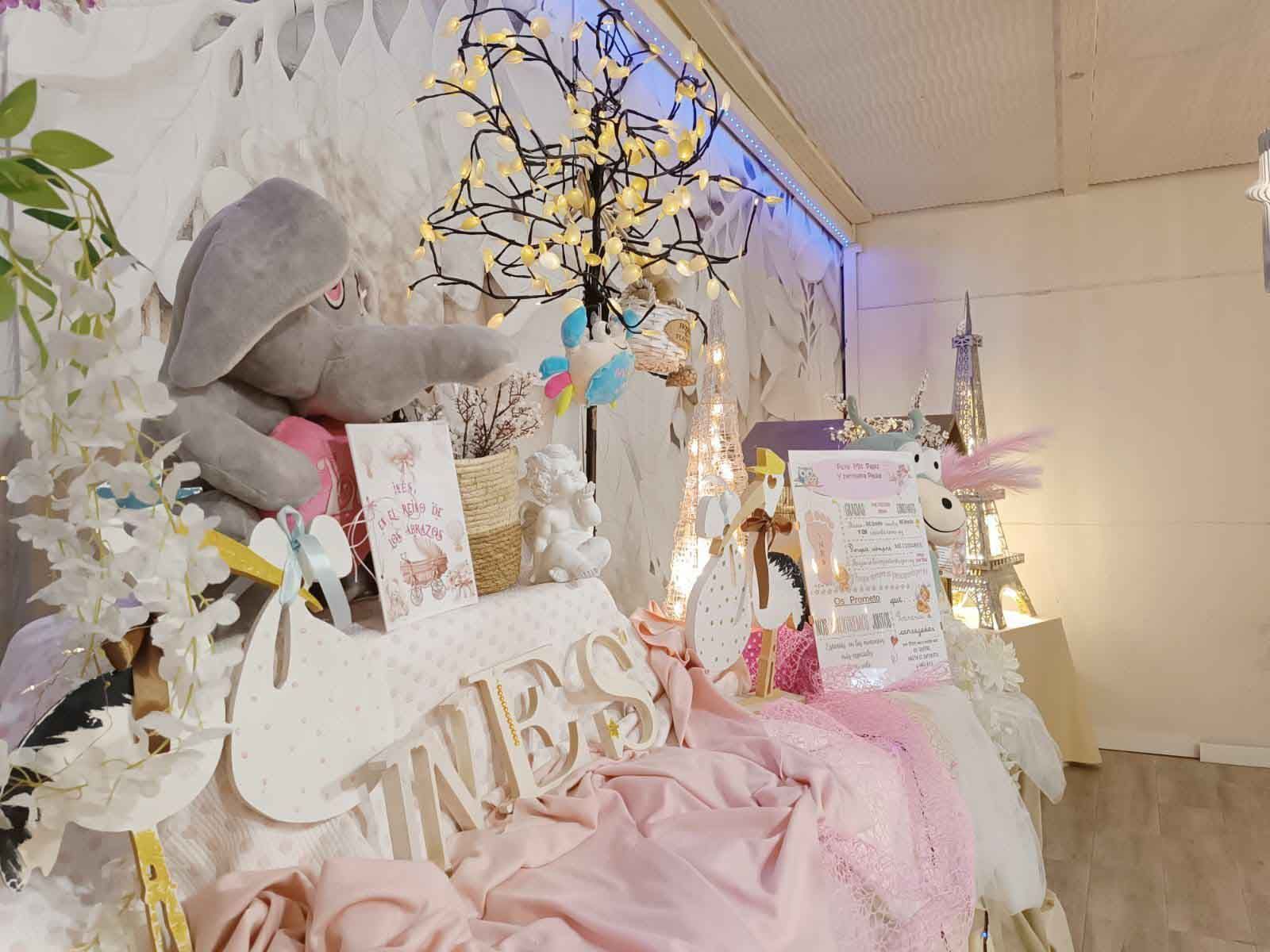 Una habitación decorada para un baby shower con un elefante de peluche, cisnes, flores y un cartel.