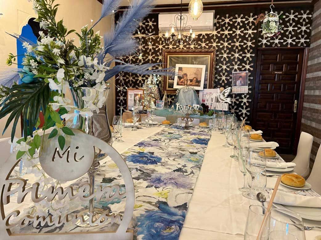 Una mesa larga con platos, vasos y flores en una habitación.