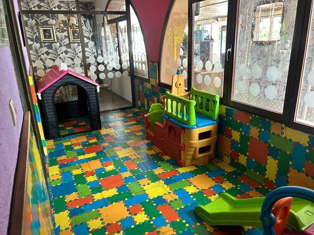 Una sala de juegos colorida con una caseta para perros, un tobogán y otros juguetes.