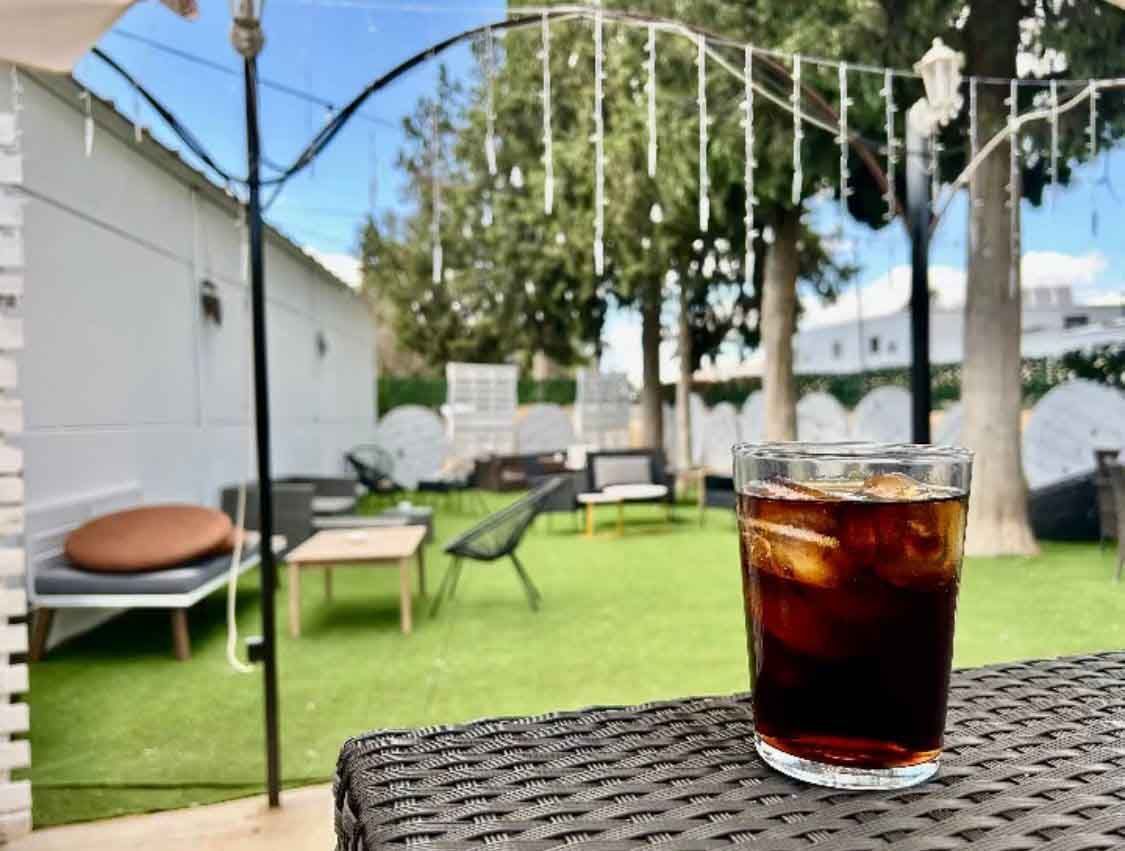 Un vaso de té helado está sobre una mesa de mimbre en un patio trasero.