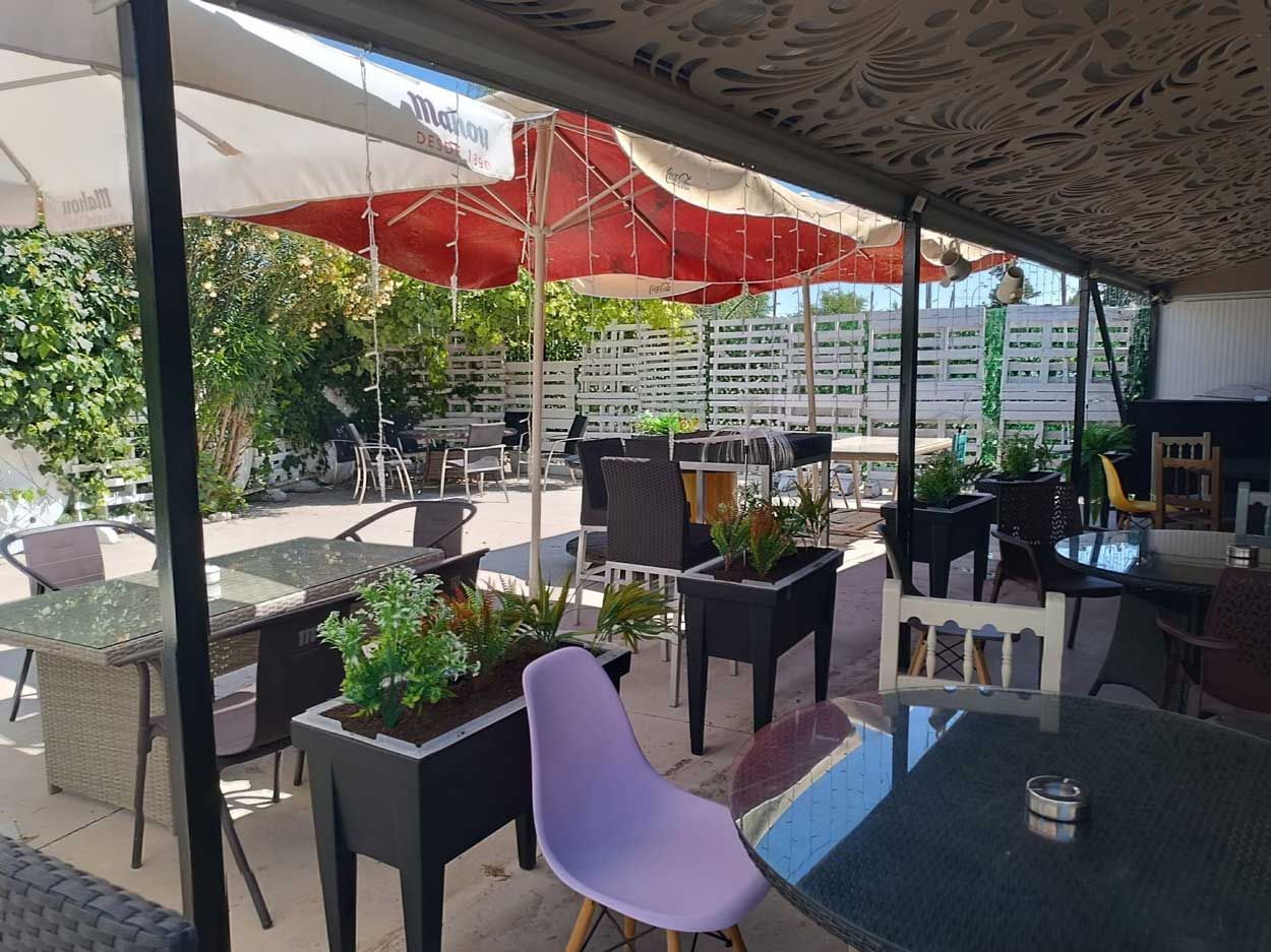 Un restaurante con mesas y sillas bajo sombrillas.