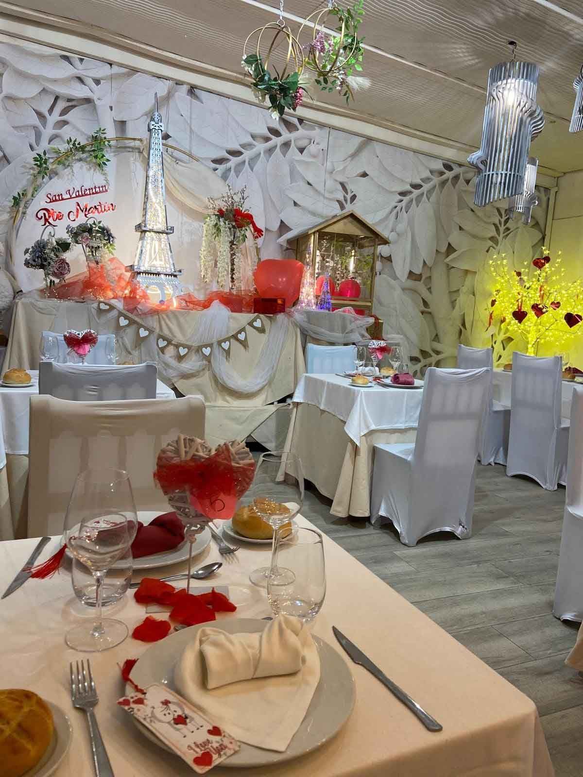 Un restaurante con mesas y sillas decoradas para el día de San Valentín.