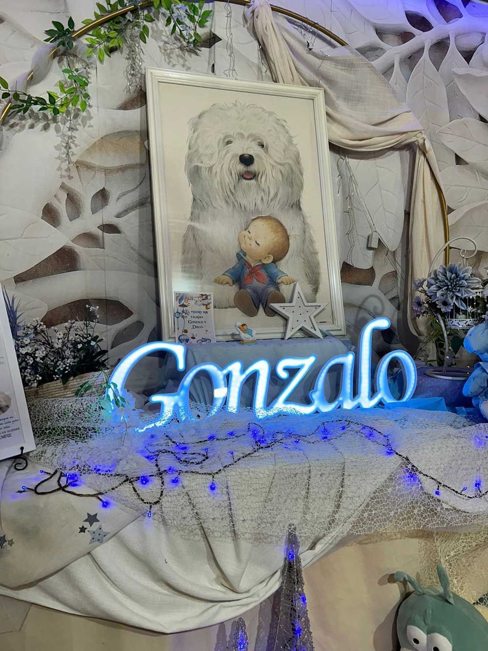 Un letrero de neón con el nombre Gonzalo está sobre una mesa al lado de una foto de un perro.