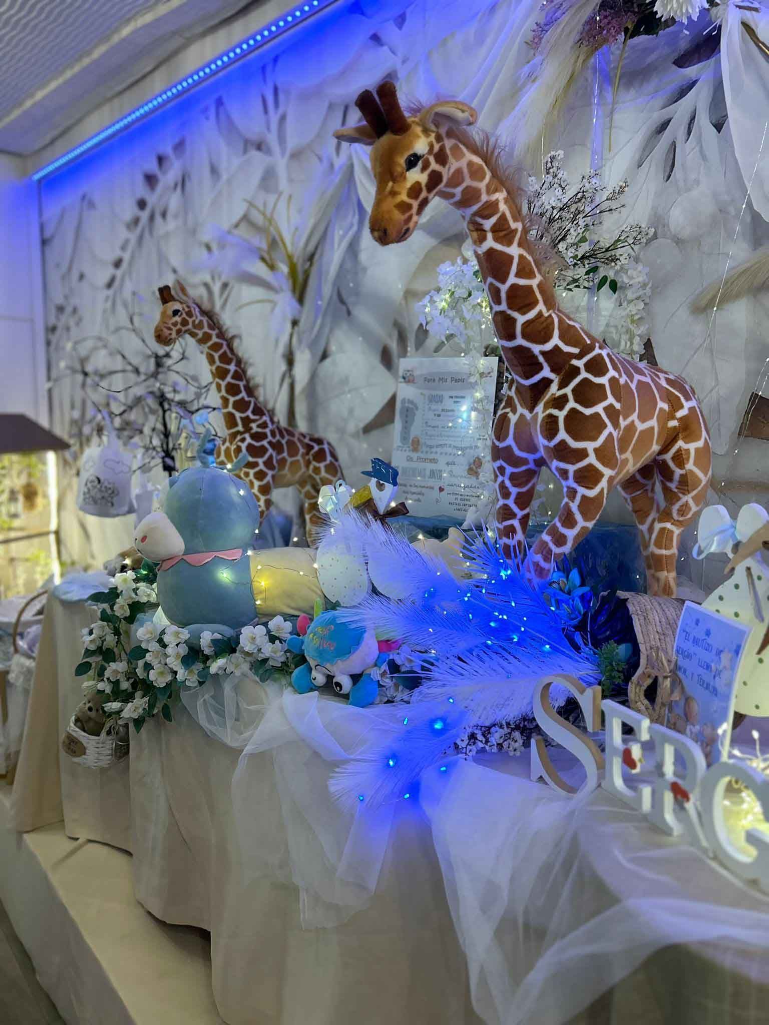 Una mesa decorada con jirafas disecadas, globos y flores.