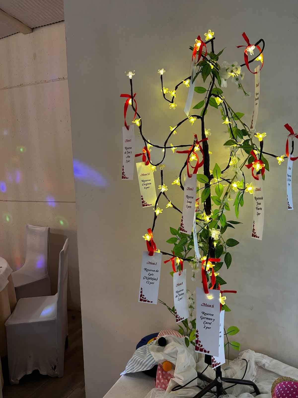 Un árbol de Navidad con luces y tarjetas está sobre una mesa.