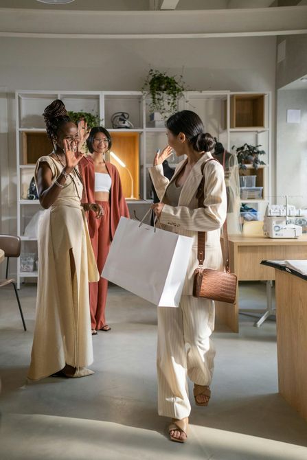 Un grupo de mujeres están de pie en una habitación sosteniendo bolsas de compras.