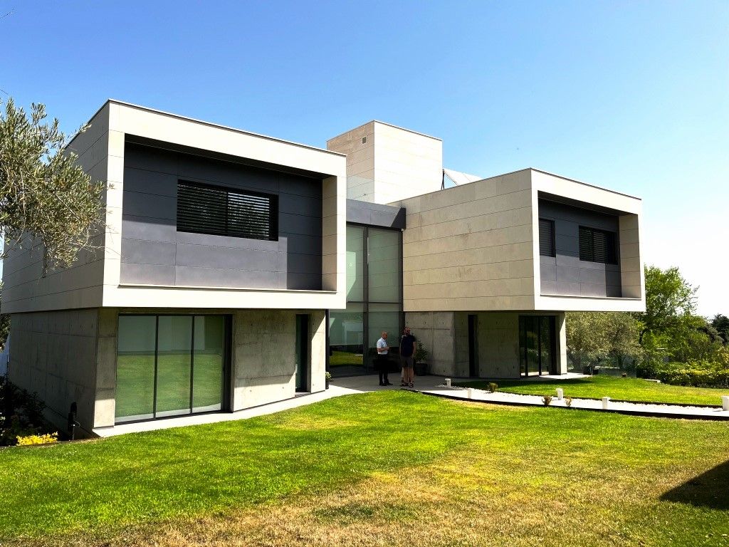 Una casa grande con muchas ventanas y mucho césped delante de ella.