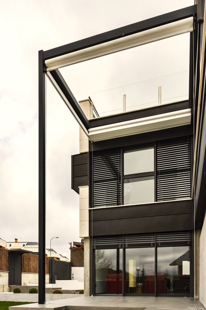Una casa moderna con una pérgola encima.