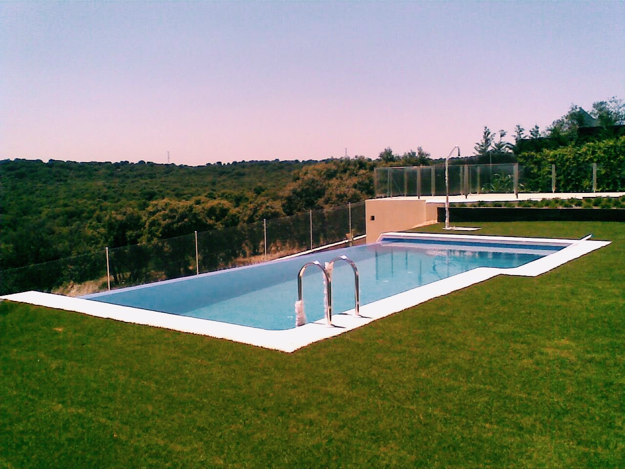 Una gran piscina rodeada de césped y árboles.