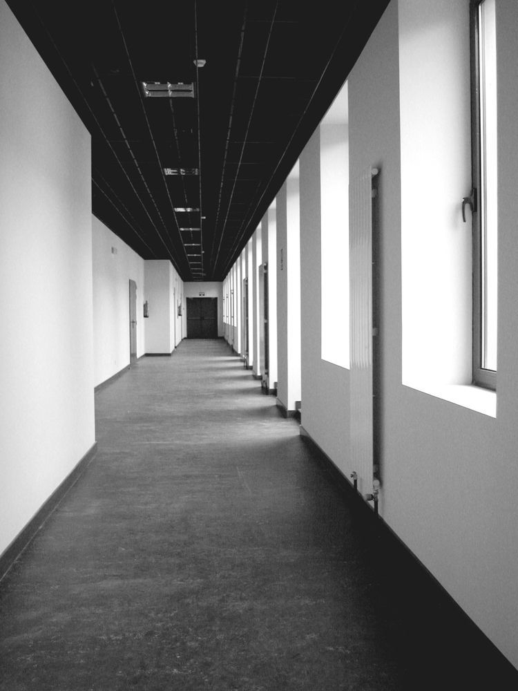 Una fotografía en blanco y negro de un pasillo vacío con ventanas.
