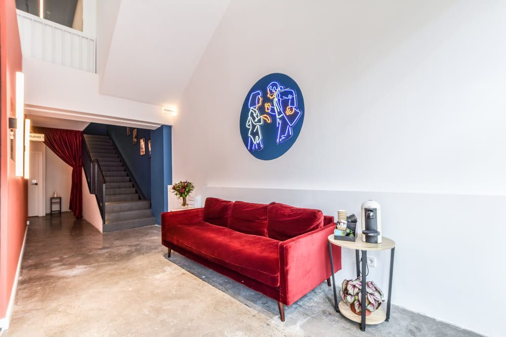 Una sala de estar con un sofá rojo, una mesa y escaleras.