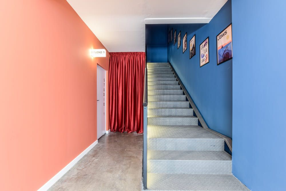 Un pasillo con escaleras y una cortina roja en la pared.