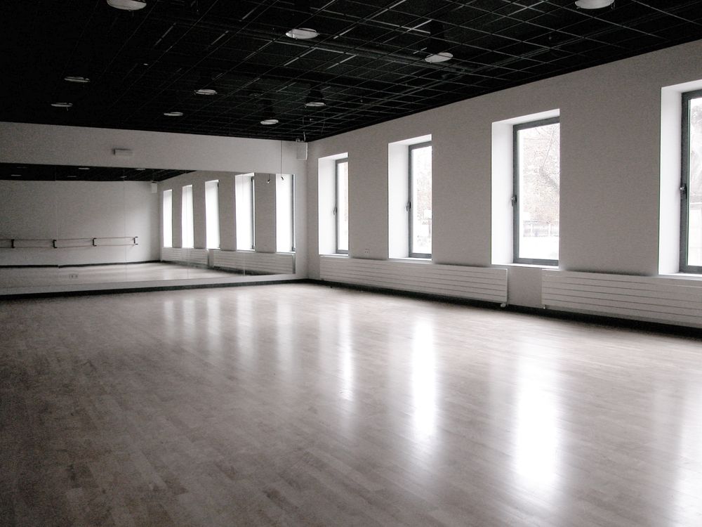 Un estudio de baile vacío con un gran espejo en la pared.