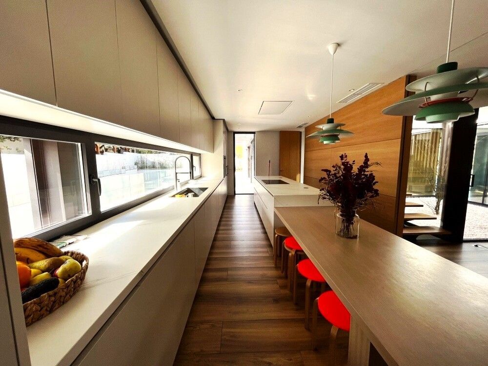 Una cocina con una mesa larga y una cesta de fruta en el mostrador.