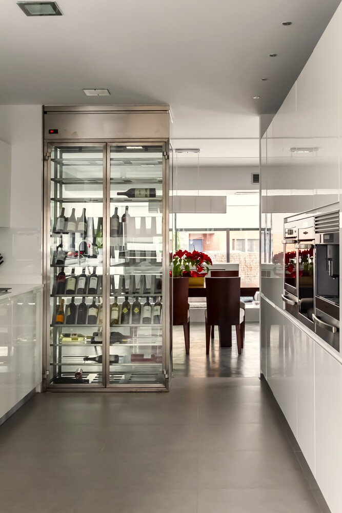 Una cocina con nevera para vinos y un comedor al fondo.