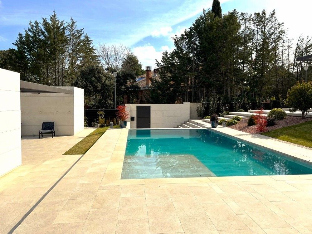 Una gran piscina en un patio trasero con árboles al fondo.