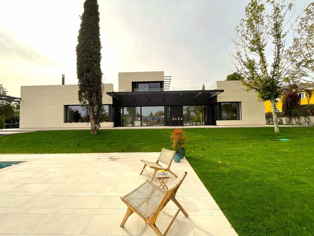 Una casa con un amplio jardín y una piscina delante de ella.