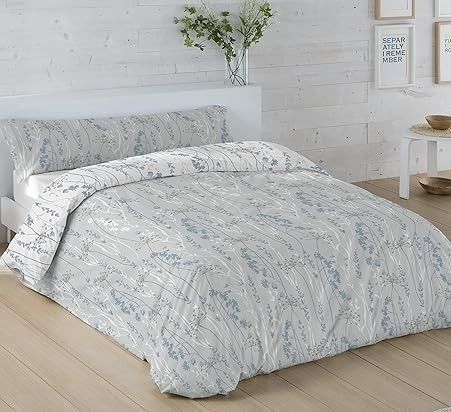 Cama con funda nórdica con estampado floral azul y blanco, colocada sobre un cabecero blanco.