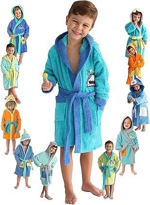 Un niño con una túnica azul sonríe, rodeado de niños con diversas túnicas con capucha de colores.