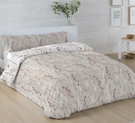 Cama con edredón y fundas de almohada estampadas en beige claro. Cabecero y suelo de madera.
