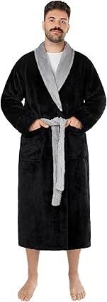 Hombre vestido con túnica negra con cuello y cinturón grises, manos en los bolsillos, descalzo.