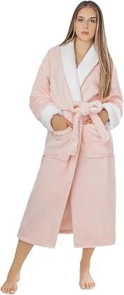 Mujer vestida con una túnica rosa claro con ribetes blancos, con las manos en los bolsillos, en el interior.