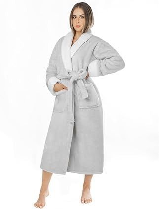 Mujer con bata de baño gris claro con ribete blanco, de pie sobre fondo blanco, sonriendo.