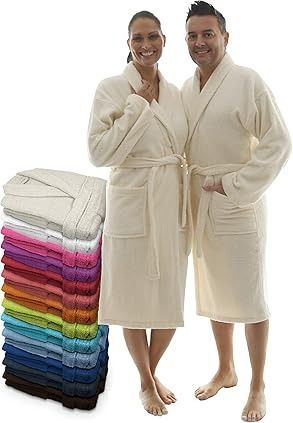 Pareja vestida con túnicas de color crema con una pila de túnicas de colores junto a ellos.