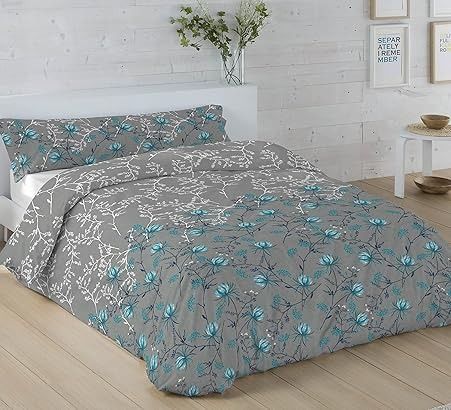 Funda de edredón y fundas de almohada con motivos florales en gris y verde azulado sobre una cama, en un dormitorio luminoso.