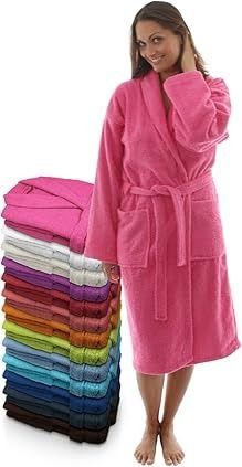 Mujer que lleva una bata de baño rosa, de pie junto a una pila de batas de baño coloridas dobladas.