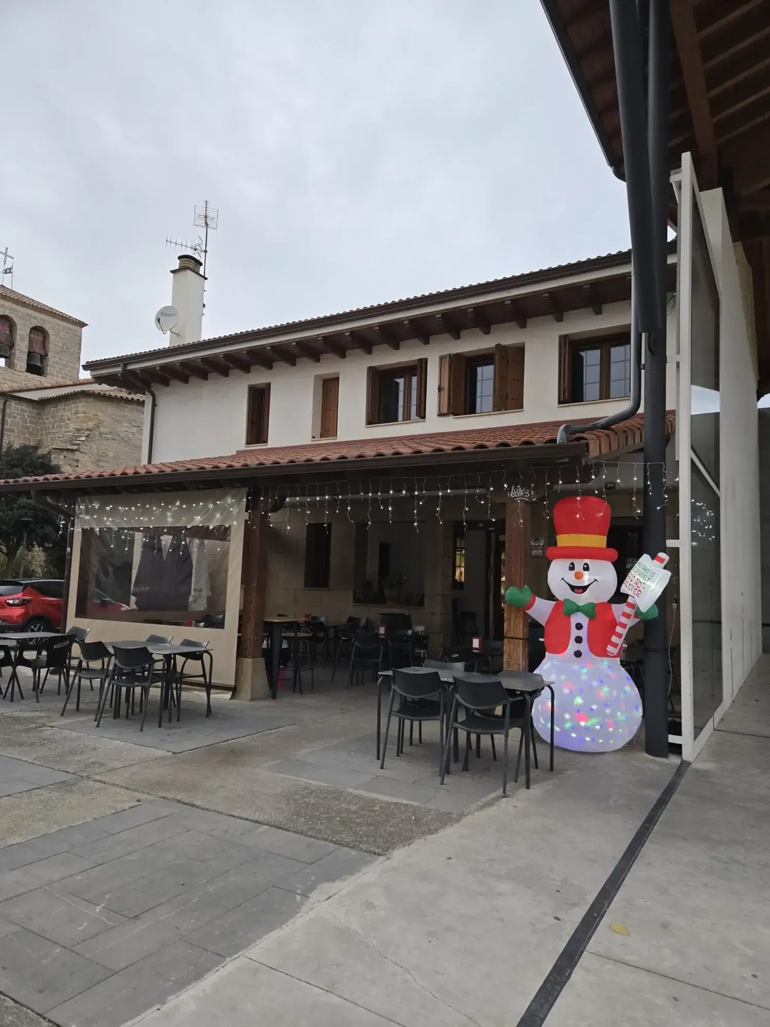 Exterior del restaurante con decoración de muñeco de nieve y asientos al aire libre.