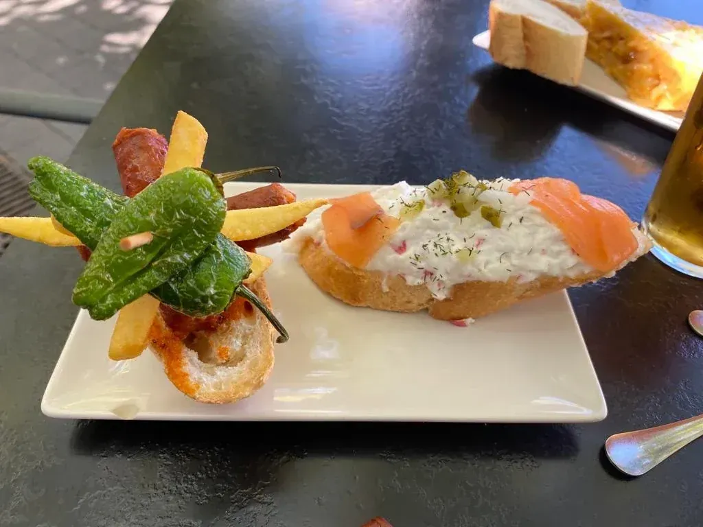 Plato de tapas: pimientos, salmón sobre pan, chorizo ​​y patatas fritas.