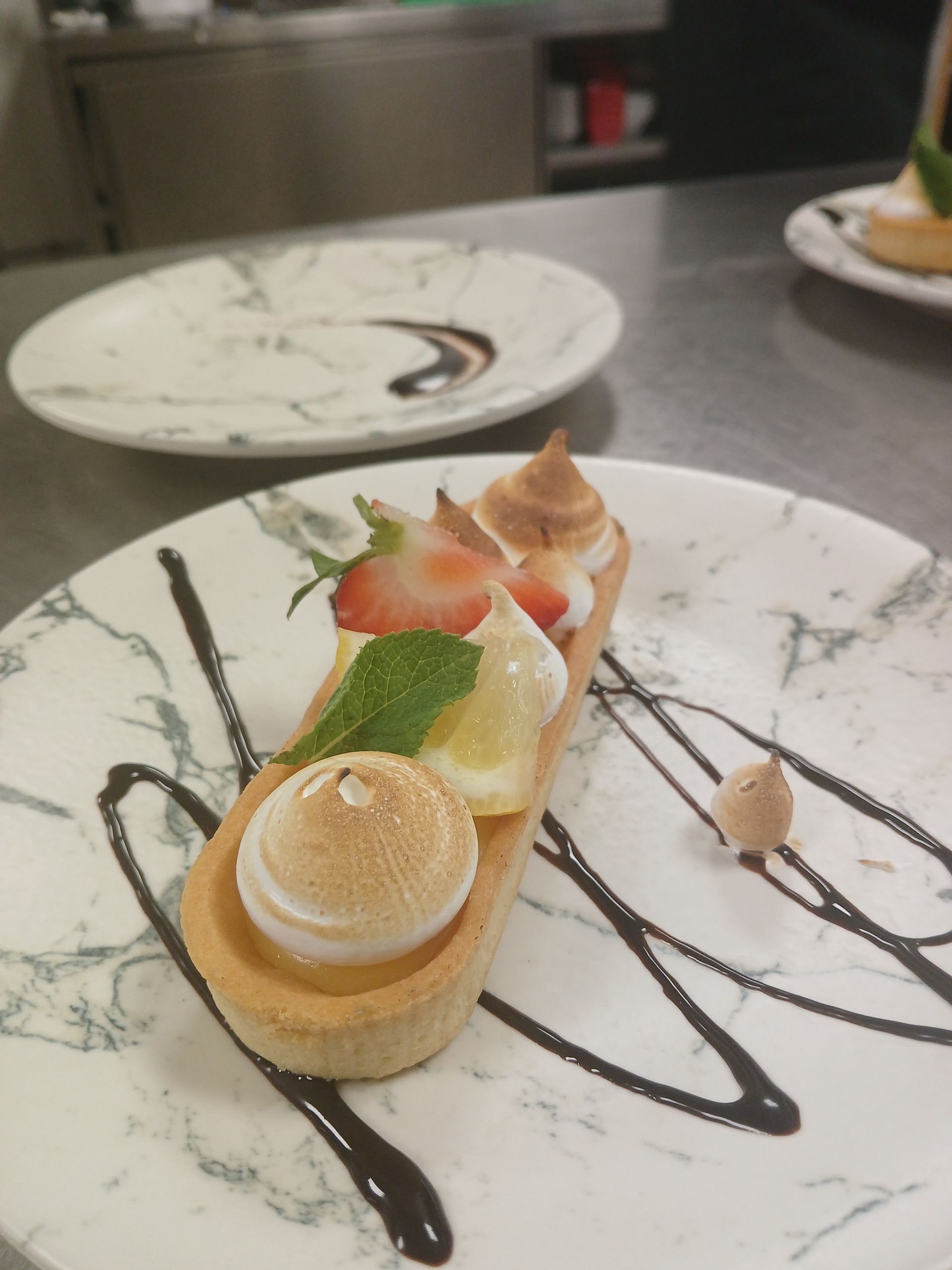 Élégant dessert à l'assiette avec crème, fruits et filet de chocolat sur une table de restaurant