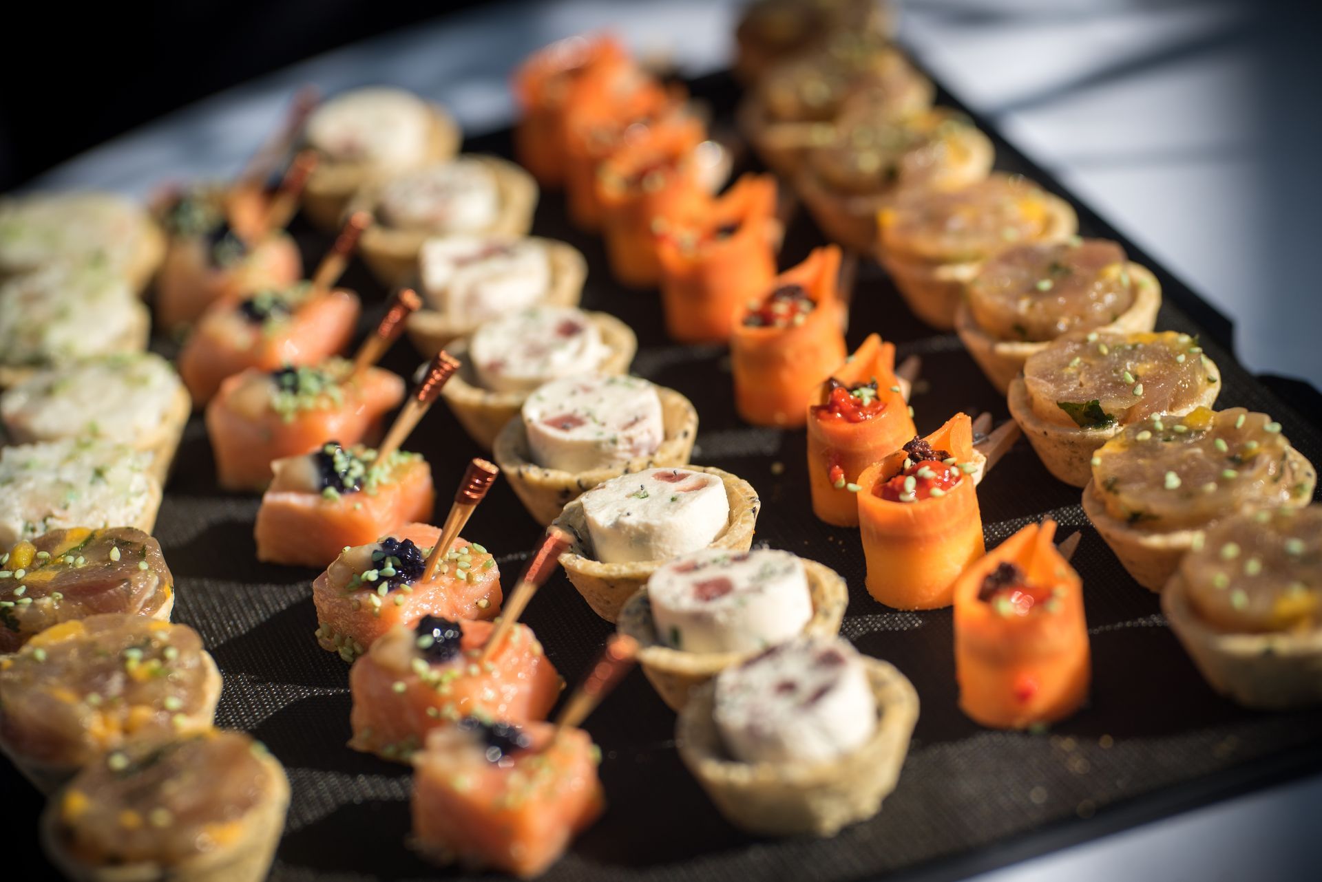 Assortiment de petits amuse-bouche en brochettes, disposés en rangées sur un plateau de service.