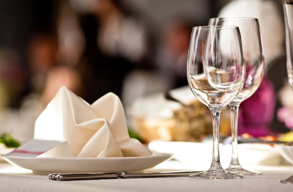 Élégante table dressée avec serviettes pliées, verres à vin et éclairage tamisé.