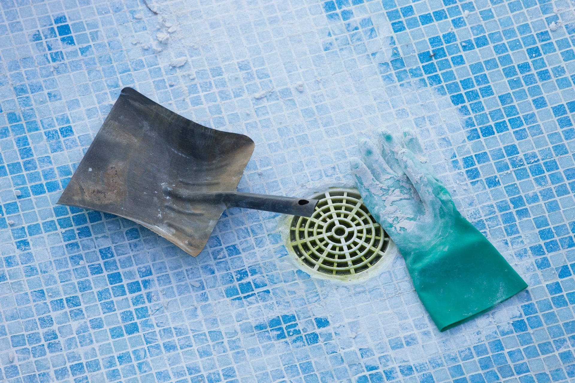 Outils de maçonnerie et gant posés au sol d'une piscine