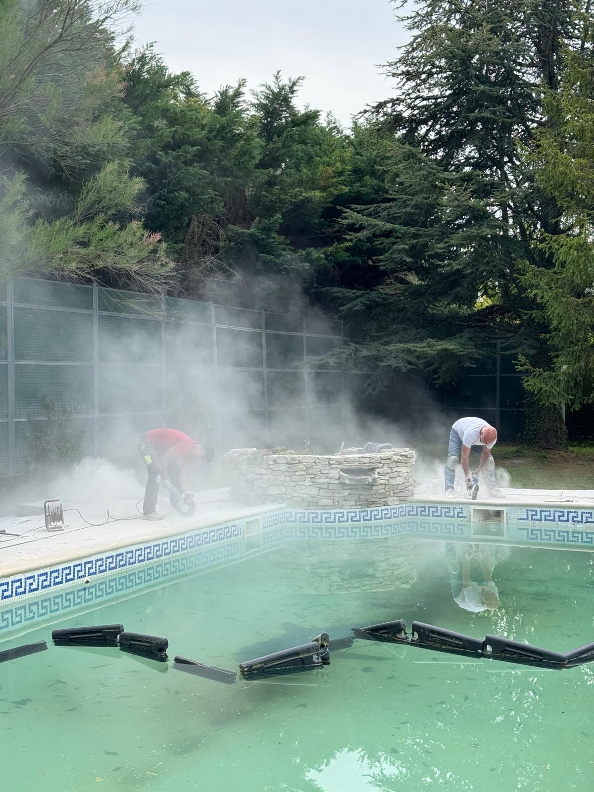 Ouvriers qui rénovent une piscine avec de la fumée