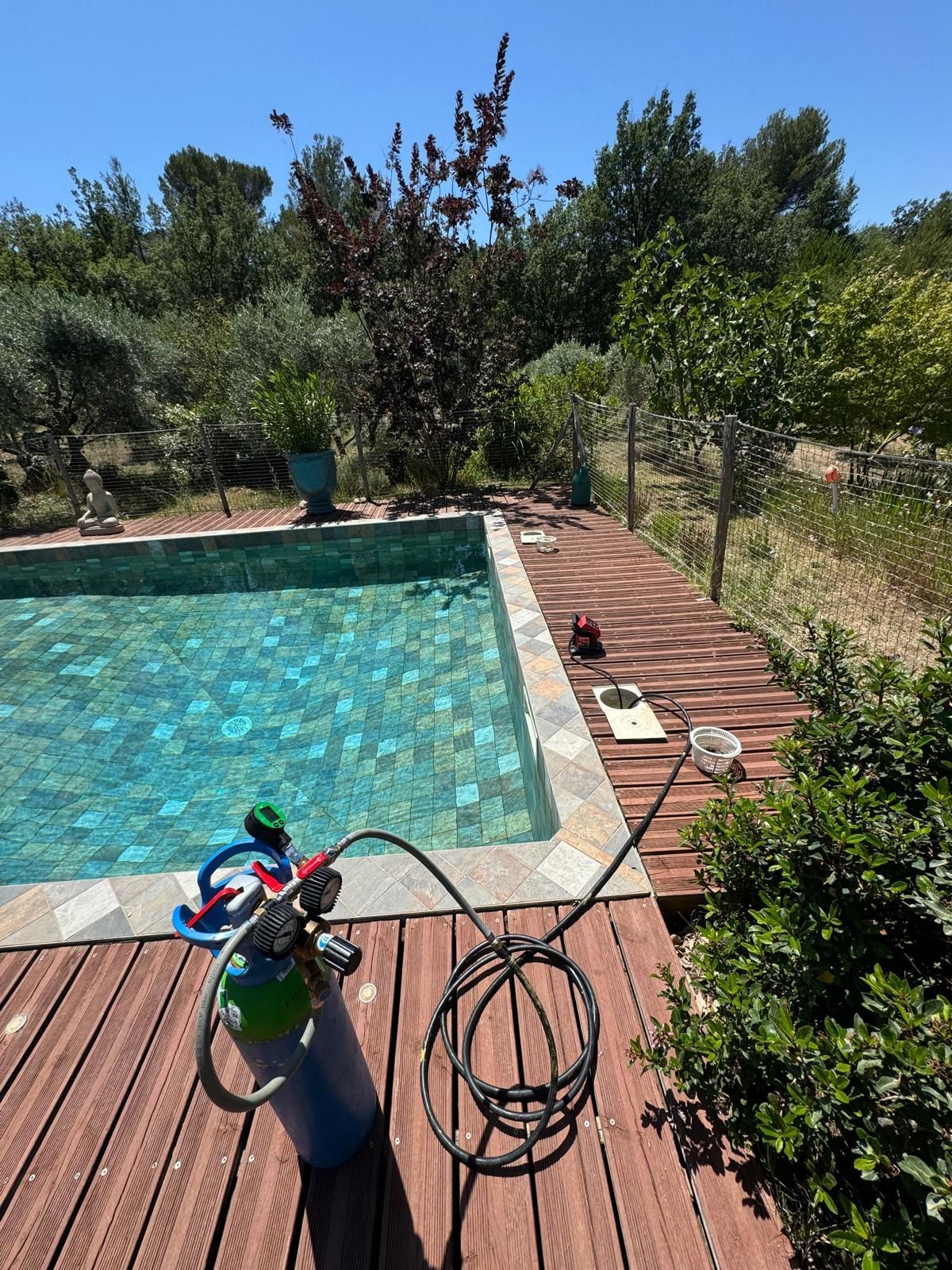 Tuyau qui rentre dans les tuyaux d'une piscine avec une terrasse en bois