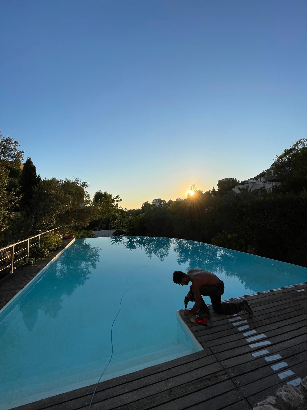 Artisan devant une piscine avec un coucher de soleil