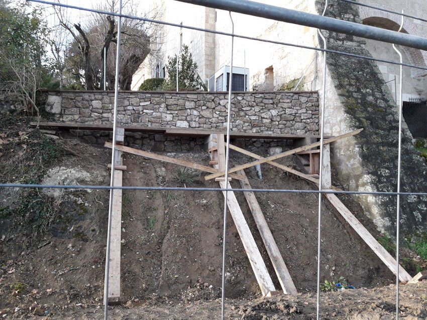 Muret en pente surélevé derrière un grillage