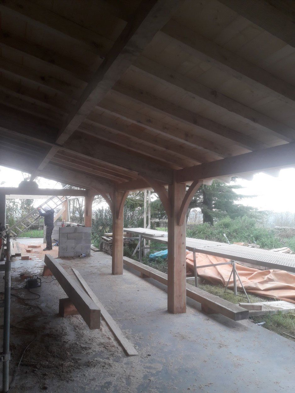 Professionnel portant une échelle sous une charpente en bois