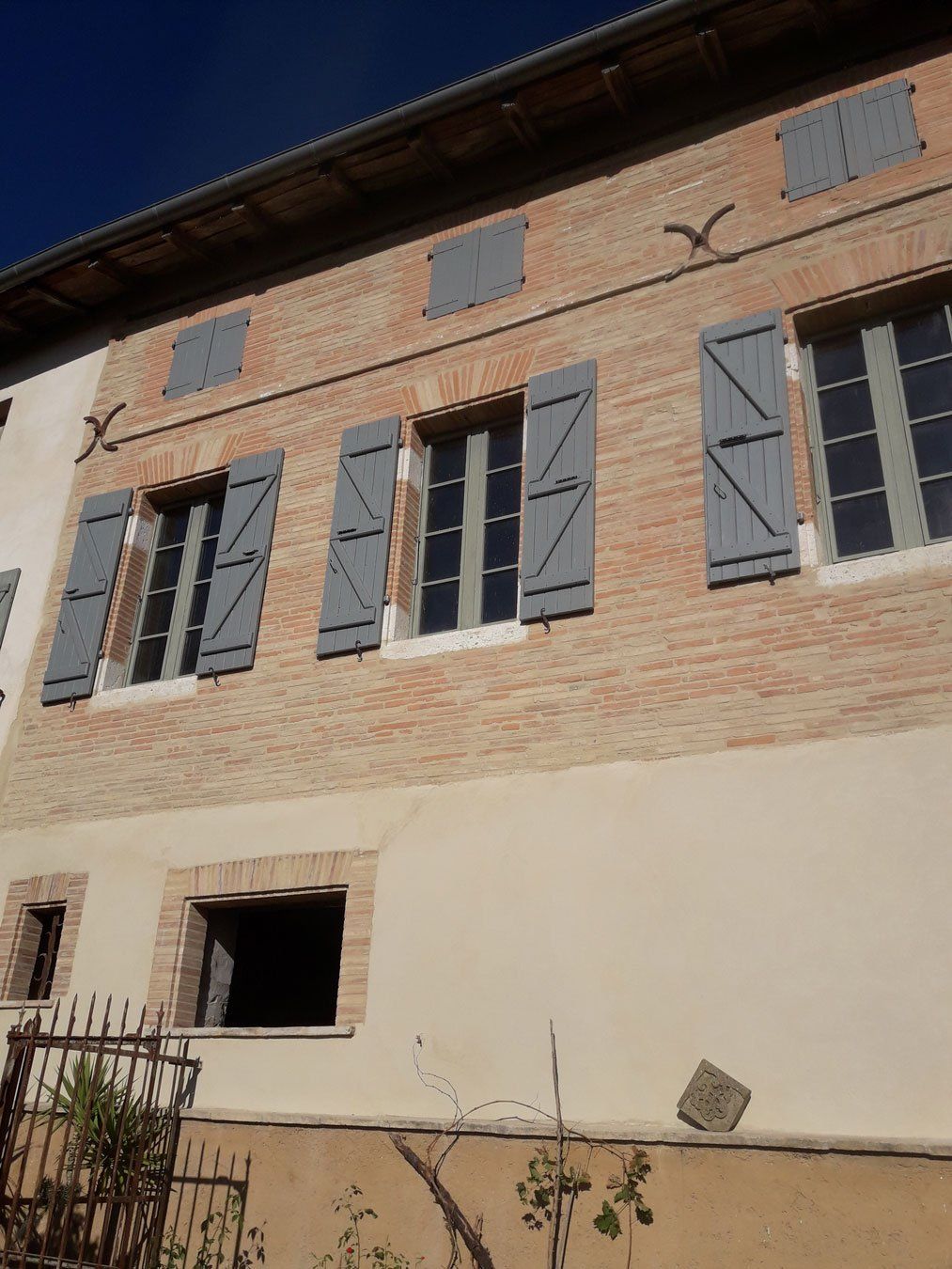 Maison avec pierres apparentes à l'étage et autour des fenêtres